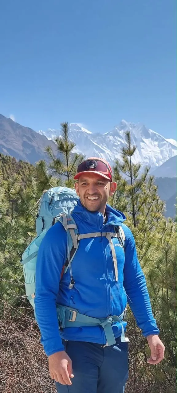 Ziad Maalem, sac au dos, souriant, devant les sommets enneigés de l’Himalaya